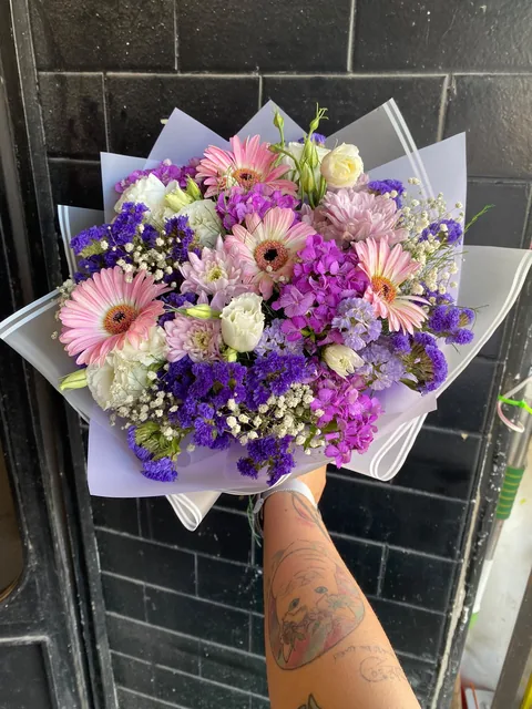 Pembe gerbera ve mor çiçeklerle hazırlanmış canlı buket