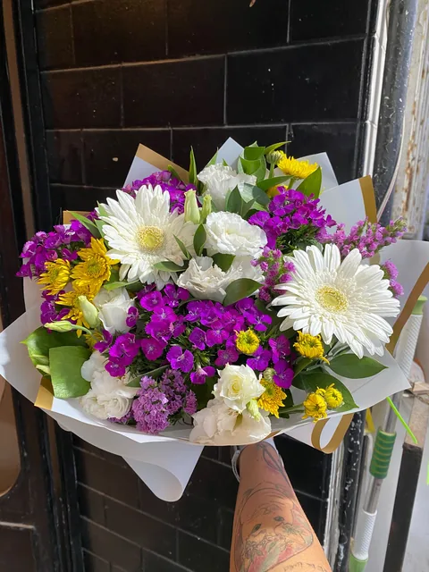 Beyaz gerbera, sarı ve mor çiçeklerden hazırlanmış canlı buket