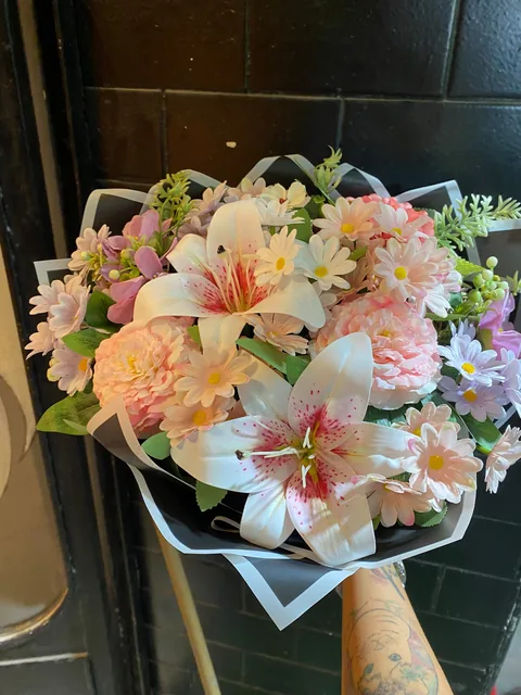 Pembe tonlarda yapay lilyum ve papatyalarla hazırlanmış dekoratif buket
